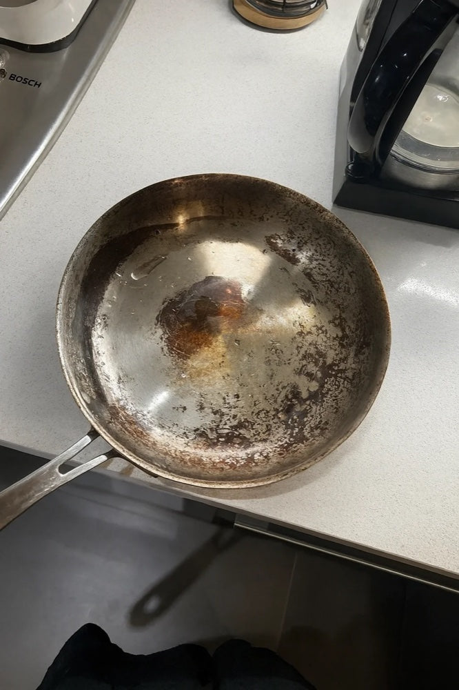 Gammal sliten stekpanna med nedbruten beläggning